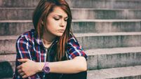 Depressed teenager sitting lonely outdoors