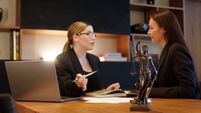 iStock-2167369596.jpg A female lawyer at her workplace communicates with a young client, discussing issues of legal significance. Consultation concept