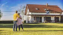 NewHomesTommyp30.jpg Couple,man and woman,hugging each other while standing on the lawn in the backyard of their new bought house,rear view,modern ho