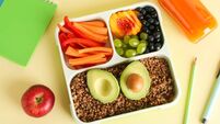 Lunch box with snacks, bottle of juice and stationery on yellow table, flat lay