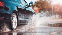 Car driving through the puddle and splashing by water.