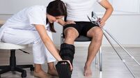 Female Doctor Putting Walking Brace On Person's Leg