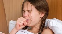 Sick child girl coughing, sitting on bed at home, close up, side view