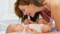 Loving Caucasian Mother Smiling at Newborn Baby Indoors in Bright and Warm Setting