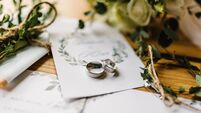 Stylish rings, flowers on wooden table background. Letters from the bride and groom. Vows. Engagement. Luxury marriage and weddi