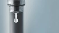 Sink faucet dripping with the water drop in focus