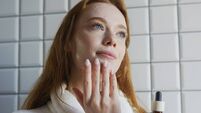 Woman diligently uses dropper to nourish skin on chin area