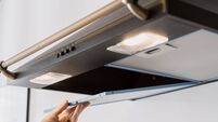 woman installing new hood filter at kitchen