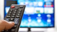 Television remote control changes channels thumb on the blue TV screen