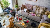Messy and dirty living room with sofa full of food, clothes and electronic devices.