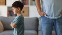 Annoyed father back to back with son ignoring each other after argue