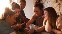 Group of friends in a rental apartment looking at a smartphone.