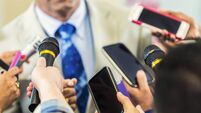 Man in suit confronted by media