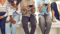 Children sitting on windowsill and ignoring real life immersed in their cell phones
