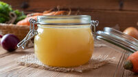 Chicken bone broth in a glass jar and fresh vegetables
