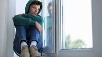 Loneliness concept. Sad teenage boy on windowsill indoors