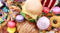 Full frame image of sweet and savoury junk foods, chicken burger, battered onion rings, pizza slices, glazed ring doughnuts, mac